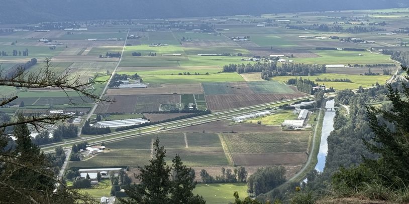 Aerial view of farmland with mountains in the background under a cloudy sky.