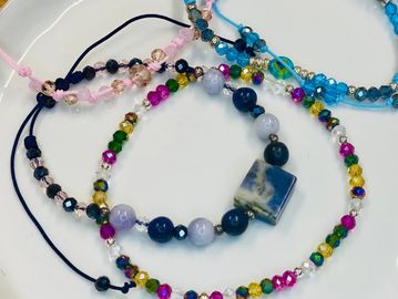 Colorful beaded bracelets with various shapes and hues on a white surface.