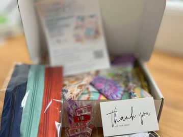 A sewing kit with zippers, clips, thread, and a thank you note in a box.