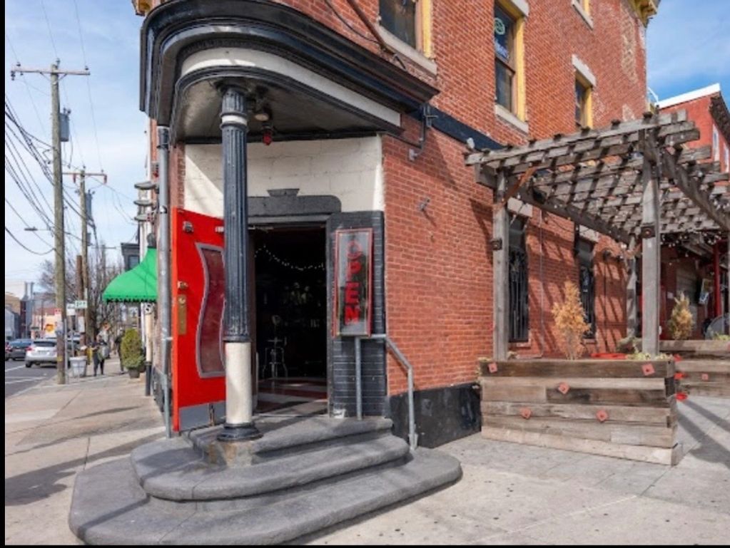 Entrance to a brick building with an open red door and an 'OPEN' sign.