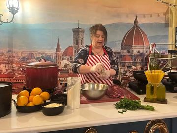 Woman preparing food in a kitchen with Italian city backdrop.