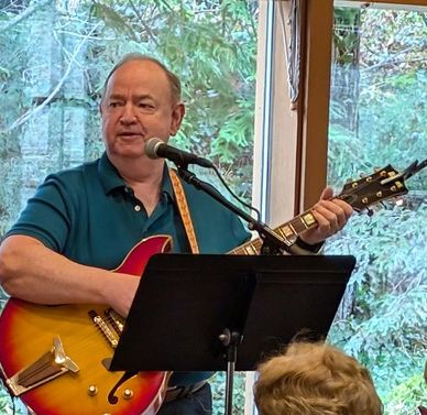 Man playing guitar and singing indoors with a microphone.