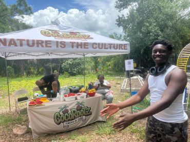 Young man presenting a farm produce stand outdoors.
