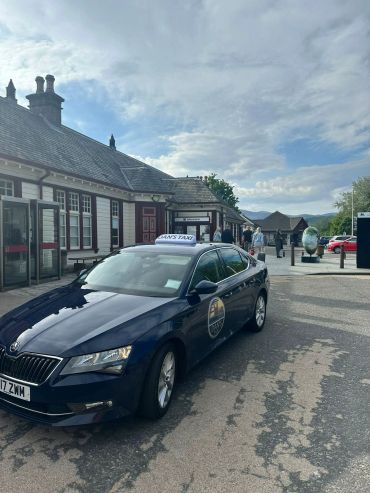 Taxi parked in front of a train station building.