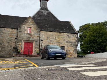 A car parked in front of a stone building with a red door.