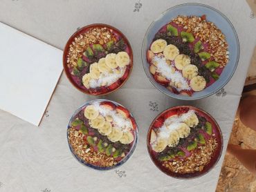 Four bowls of fruit and granola smoothie bowls on a table.
