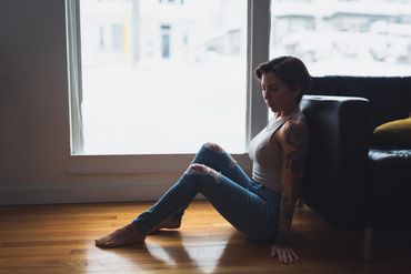 Woman with short hair sits in front of a window. 