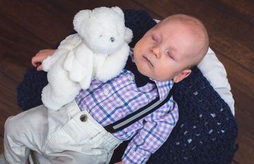 Baby boy sleeps with an angel teddy bear. 