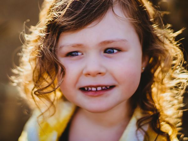 Little girl with curly hair and blue eyes looks to the side