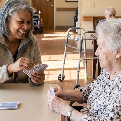 Two elderly women playing cards and enjoying each other's company.