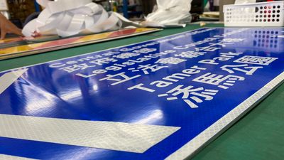 A close-up of a blue road sign with Japanese and English text on a table.