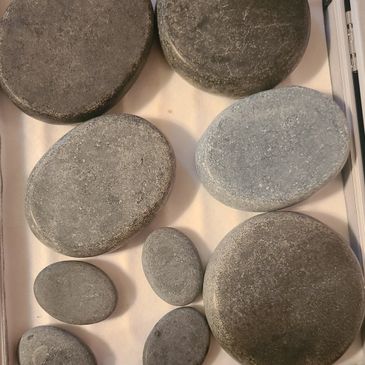 Set of smooth, oval-shaped massage stones in a box.