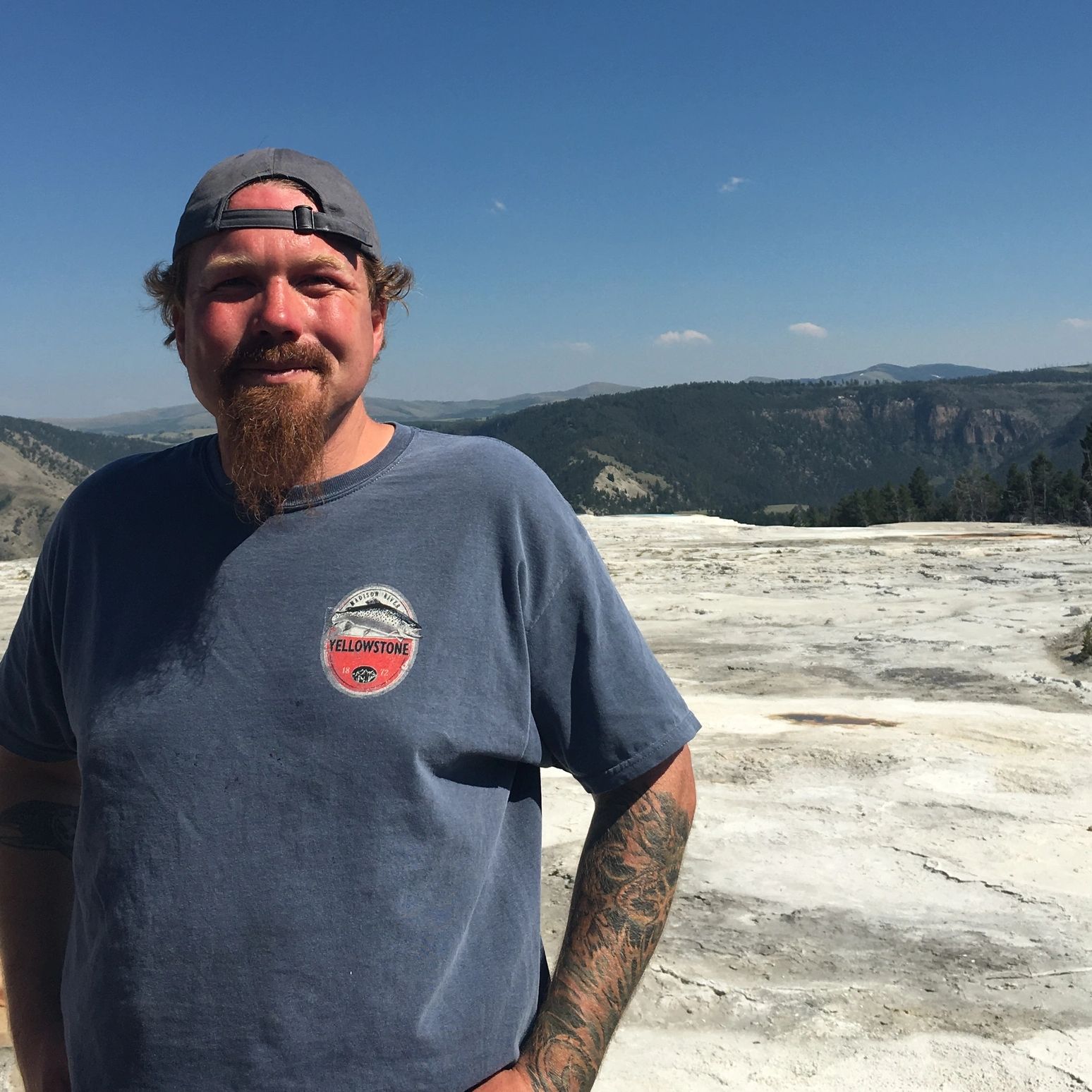 Man standing on mountain top smiling into camera.