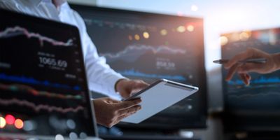 Energy trading analysis: A person using a tablet to review energy data with charts displayed