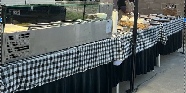 Long buffet table with checkered tablecloth and serving trays.