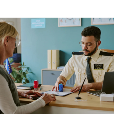 Security officer stamping documents for a woman at a visa application center.