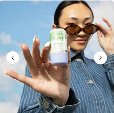Person holding a skincare product outdoors.
