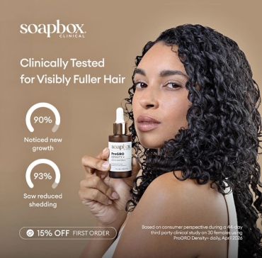Woman with curly hair holding Soapbox Clinical hair product.