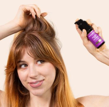 Woman applying hair serum to her roots.
