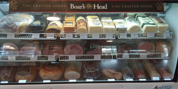Display case with various Boar's Head cheeses and deli meats.