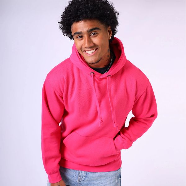 Young man smiling in a bright pink hoodie and light blue jeans.