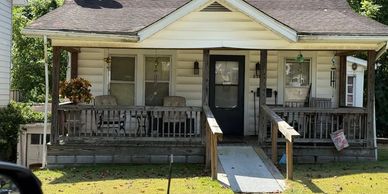 A small house with a wooden porch and ramp in front.