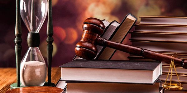 Gavel, books, hourglass, and scales symbolizing justice and law.