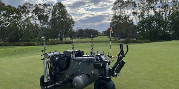 Autonomous golf cart on a green golf course under a cloudy sky.