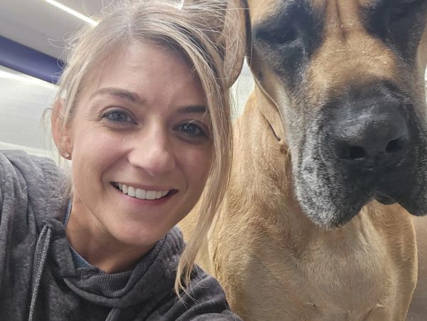 Smiling woman taking a close selfie with a large dog.