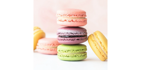 Colorful macarons stacked and arranged on a white surface with pastel background.