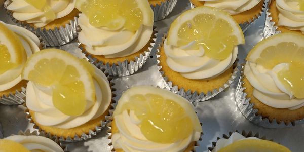 Lemon cupcakes with white frosting and lemon slices on top.