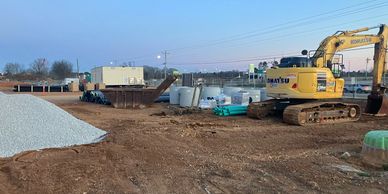 Construction site with excavator and building materials at dusk.