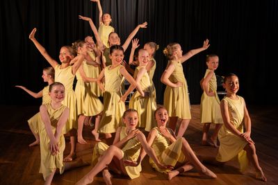 Group of young dancers in yellow dresses performing.