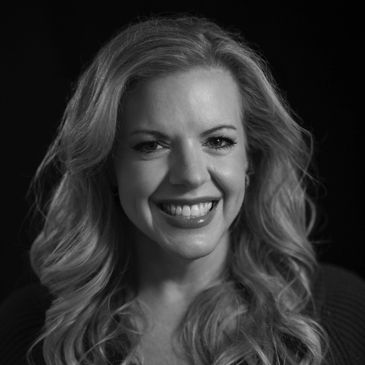 Black and white portrait of a smiling woman with wavy hair.