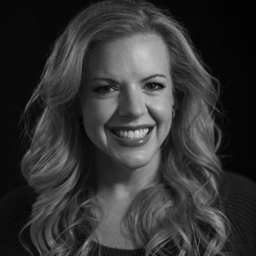 Black and white portrait of a smiling woman with wavy hair.