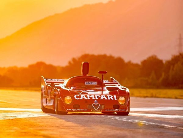 A red Campari race car on a track during sunset.