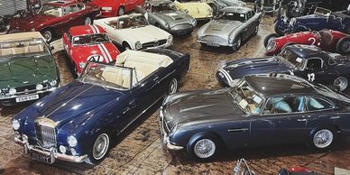 Classic luxury and sports cars displayed indoors on a polished floor.