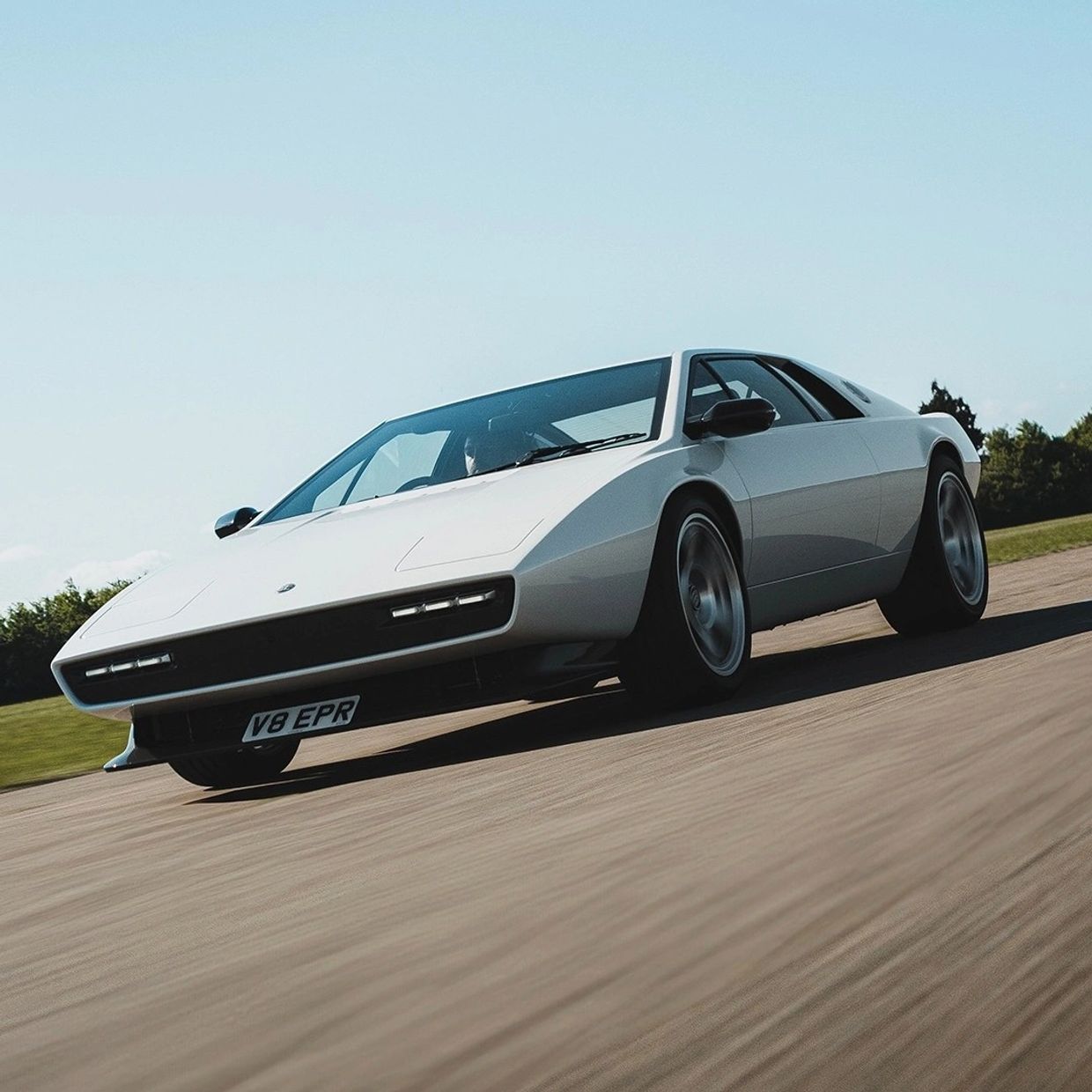 White vintage sports car driving on road.