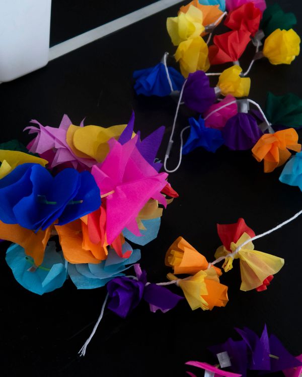 Colorful paper flower garlands laid out on a dark surface.