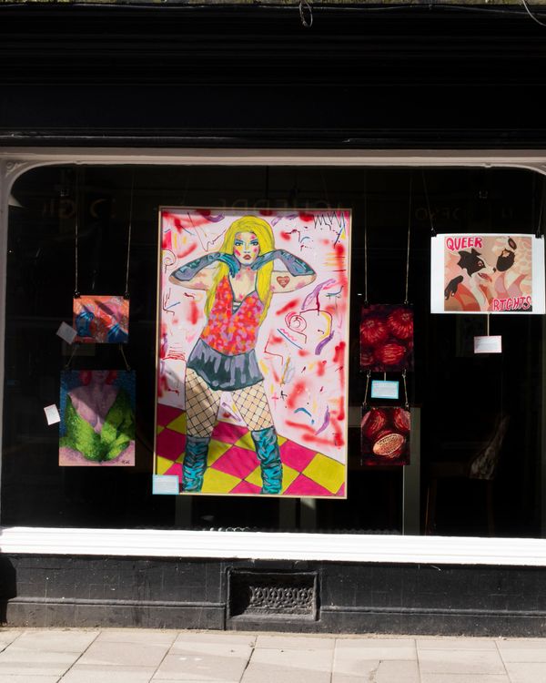 Colorful art display in a gallery window with a bold central figure.