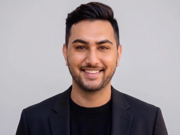 Smiling man in black blazer and shirt.