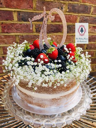 Naked buttercream cake topped with fruit and flowers