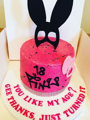 Pink buttercream cake with black paint splashes themed with Ariana Grande topper