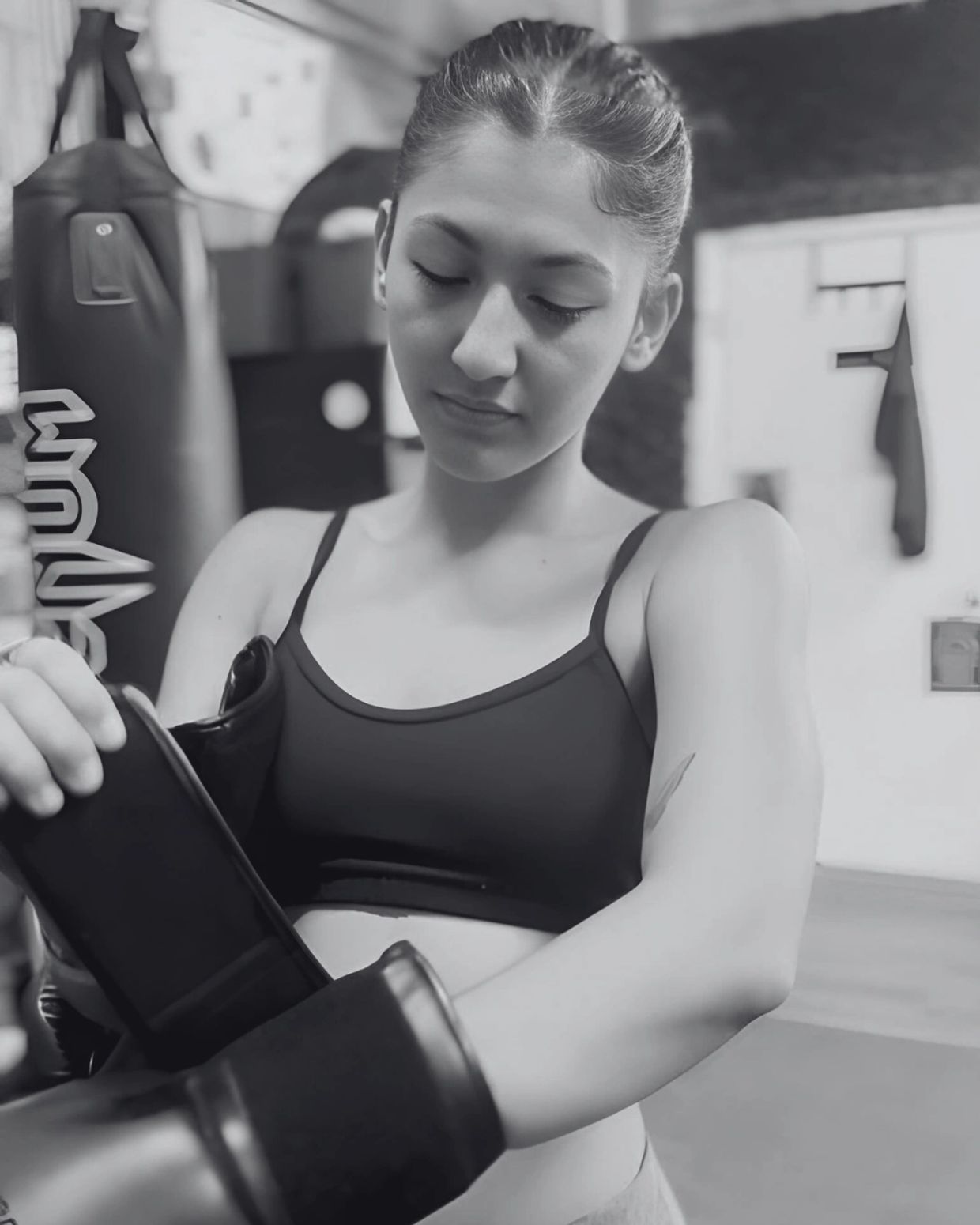 Young woman putting on boxing gloves in a gym.