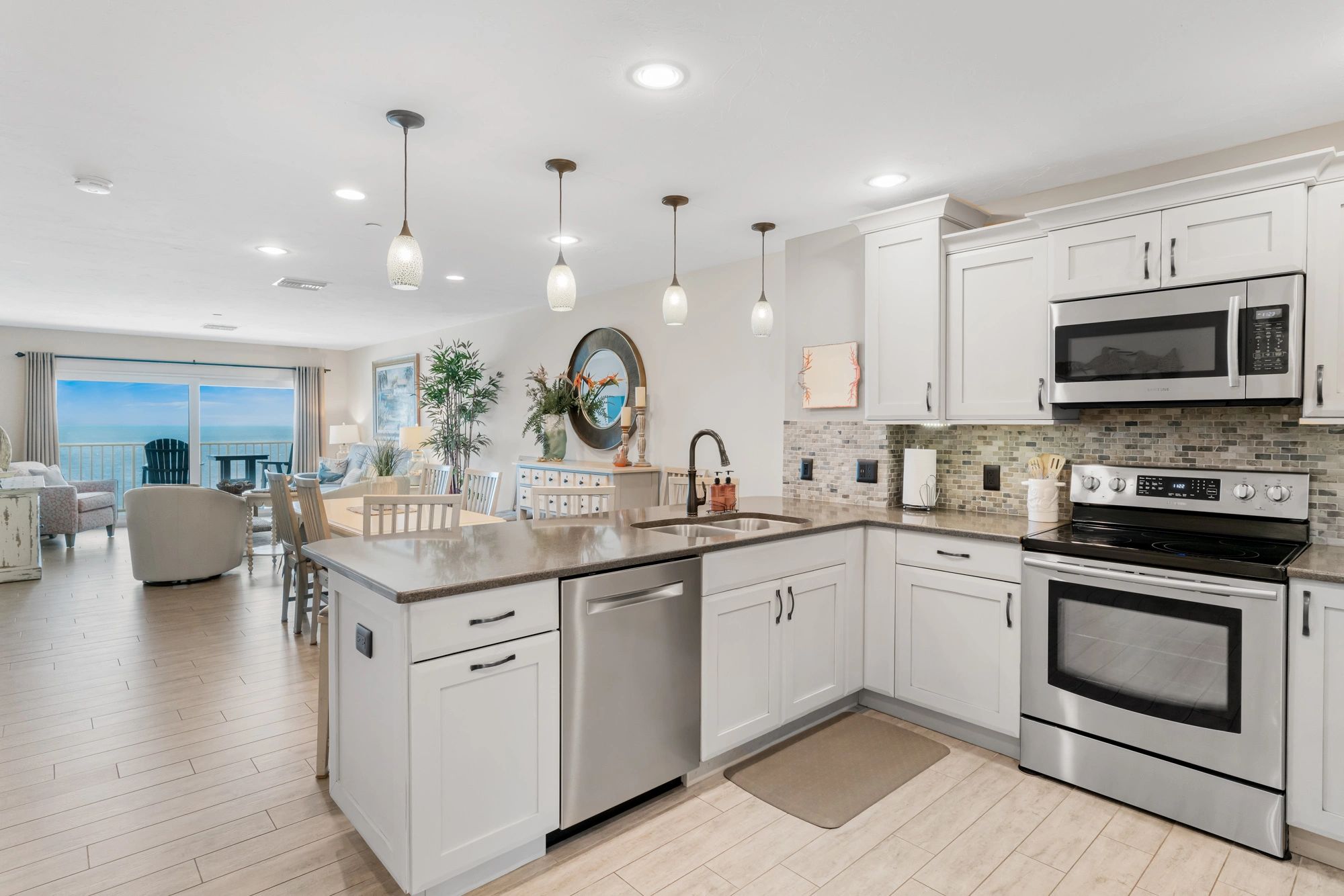 Coastal kitchen remodel with white shaker cabinets and open living area by True North Building Group