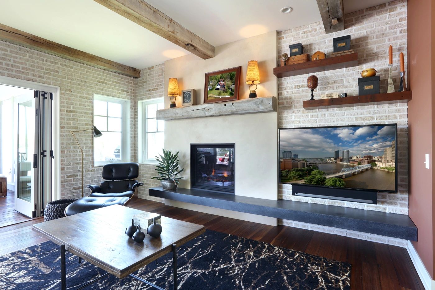 Living room with see-through fireplace, reclaimed beam mantel, and whitewashed brick walls