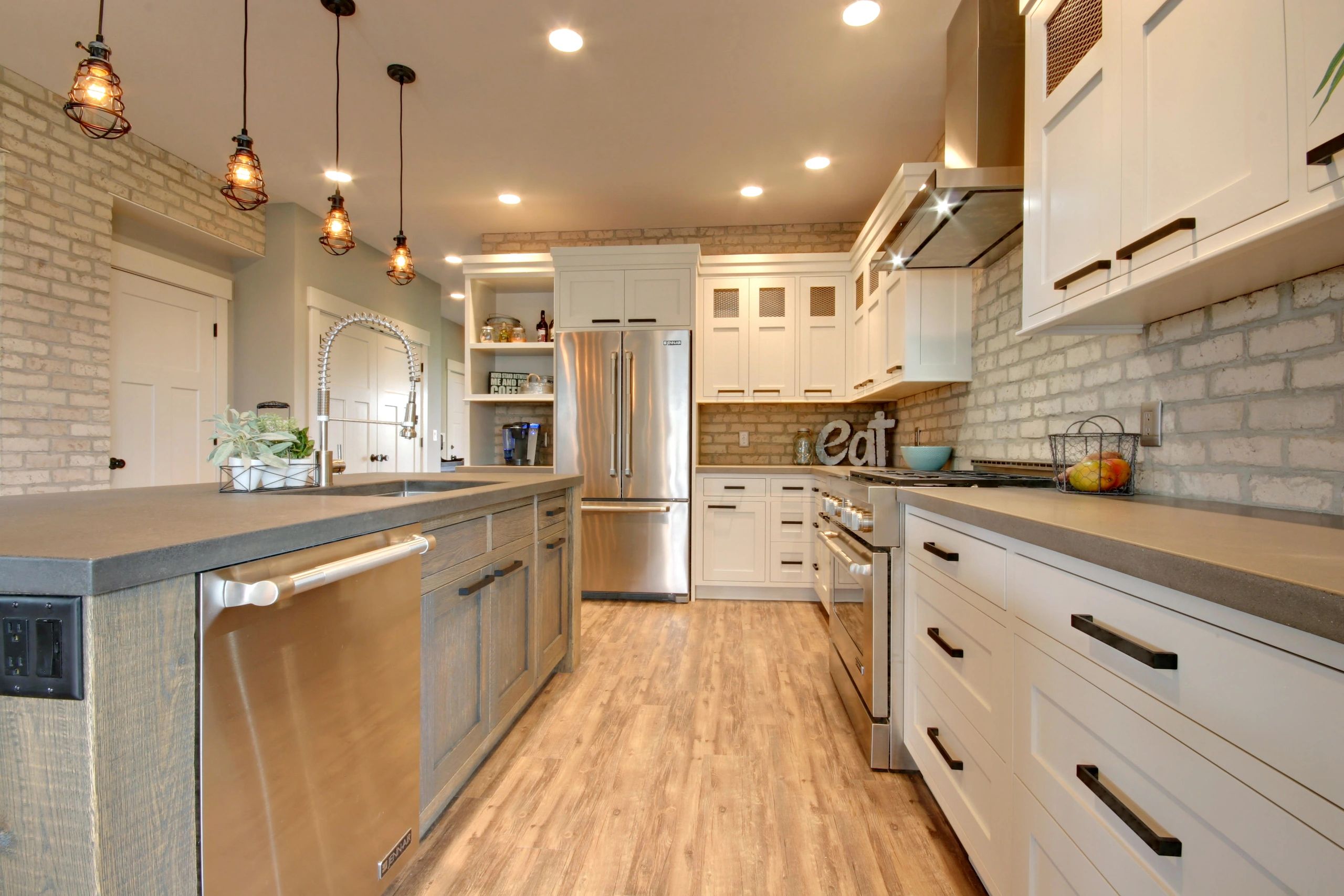 Custom kitchen with brick walls, concrete counters, two-tone cabinets by True North Building Group
