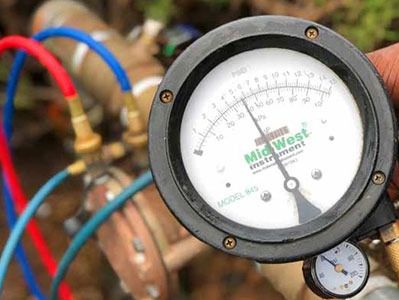 Close-up of a pressure gauge with colorful hoses attached.