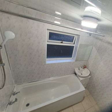 Clean bathroom with bathtub, window, and sink.
