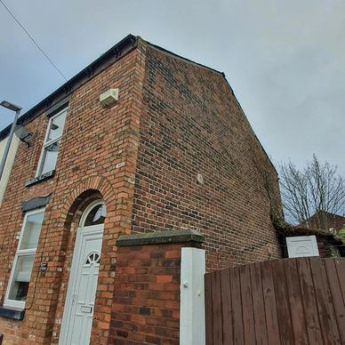 Brick house corner with white door and windows.